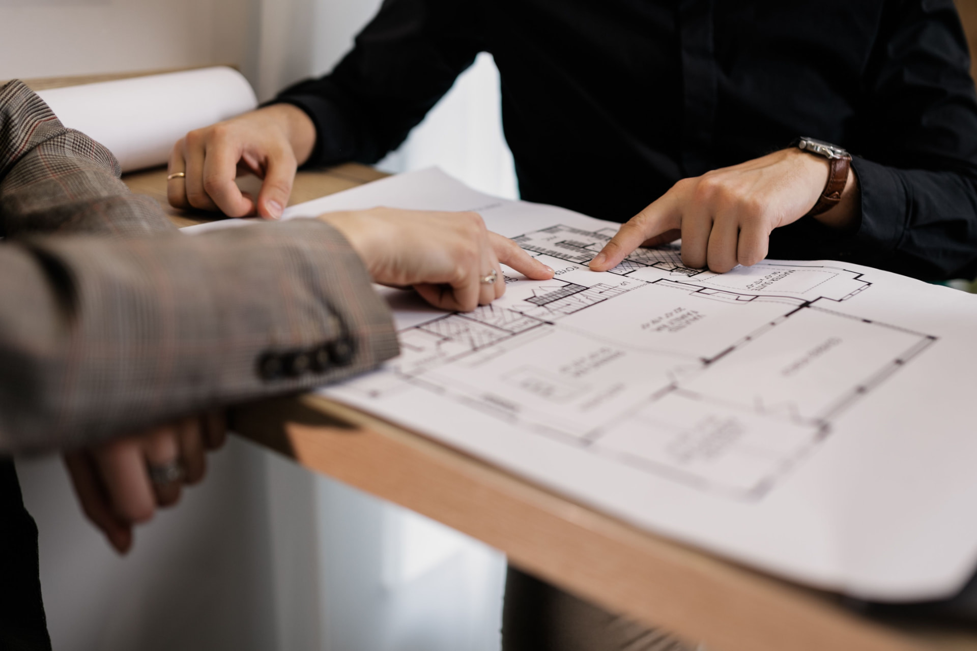 Hands pointing at architectural floor plans during a renovation planning meeting